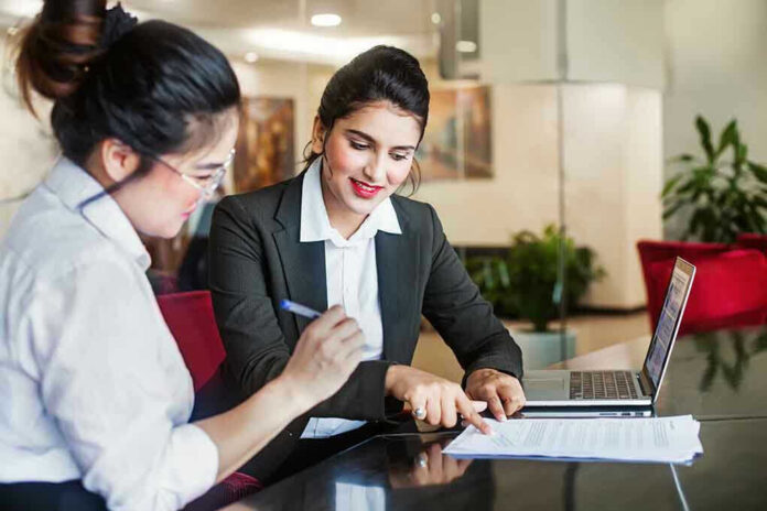 1163401579 Two women discussing papers at a laptop