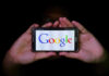 Hands holding smartphone displaying Google logo