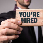 Person holding a Youre Hired sign