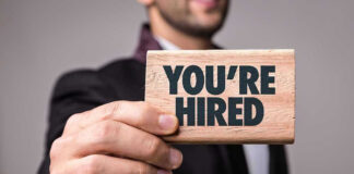 Person holding a Youre Hired sign