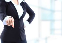 A professional woman in a suit pointing with her right hand
