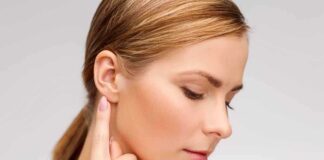 Profile view of a woman gently touching her ear with a thoughtful expression