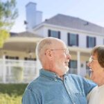 Elderly couple smiling and enjoying each others company in front of a house