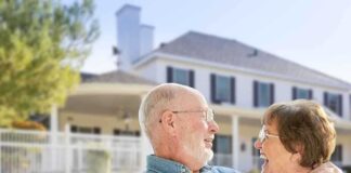 Elderly couple smiling and enjoying each others company in front of a house